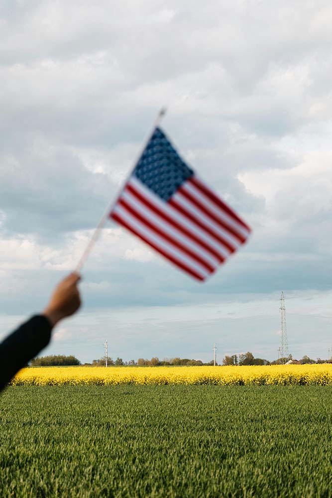 An American Flag held above a field of crops in rural Northern America